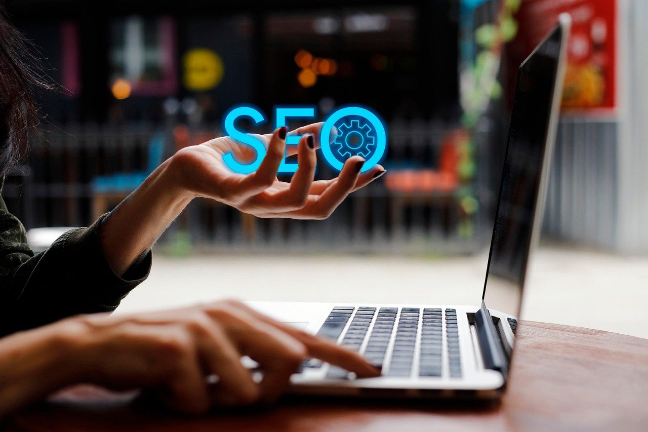 digital marketing and web design specialist in Kerala this is my focus keyword in a table someone is typing a lap on other hand he is holding seo letters in blue colour